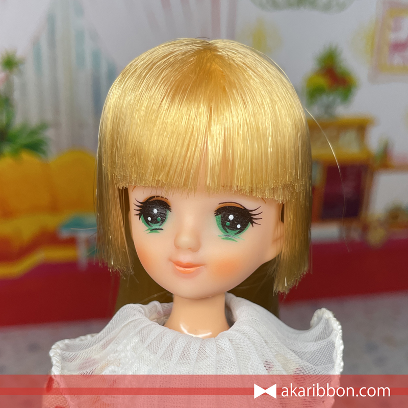 ファッションペアの水原リナちゃん顔アップ。長い金髪の姫カットとおすまし顔が印象的で、才色兼備なキャラクターを象徴するような儚げな表情。